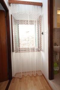 a window with a white curtain in a room at Apartments with a parking space Veli Losinj, Losinj - 8060 in Veli Lošinj