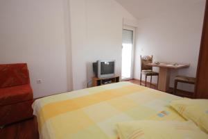 a bedroom with a bed and a tv and a chair at Studio Pasman 8215a in Pašman