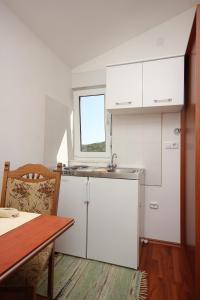 a kitchen with white cabinets and a table and a window at Studio Pasman 8215a in Pašman