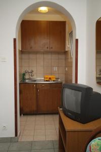 a kitchen with a tv on a table with a sink at Studio Mali Losinj 7953b in Mali Lošinj