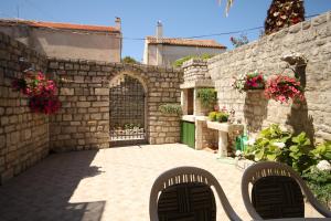 un patio con 2 sillas y una pared de piedra en Apartments by the sea Osor, Losinj - 8088, en Nerezine