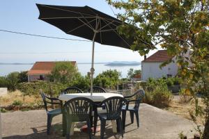 a table and chairs with an umbrella on a patio at Apartments with a parking space Savar, Dugi otok - 8127 in Savar