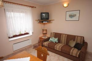 a living room with a couch and a tv at Apartments by the sea Mali Losinj (Losinj) - 7974 in Mali Lošinj