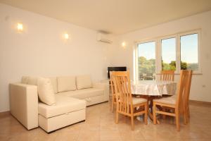 een woonkamer met een bank en een tafel en stoelen bij Seaside apartments with a swimming pool Ugljan - 829 in Ugljan