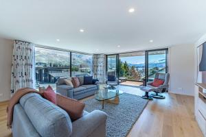 a living room with a couch and chairs and windows at Central Vista in Wanaka in Wanaka