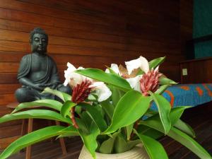 posąg buddy siedzącej obok rośliny w obiekcie JARDIM UXUA w mieście Ilha de Boipeba
