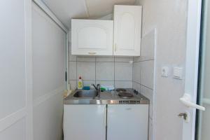 Elle comprend une petite cuisine avec un évier et des placards blancs. dans l'établissement Apartment Podaca 6677d, à Podaca