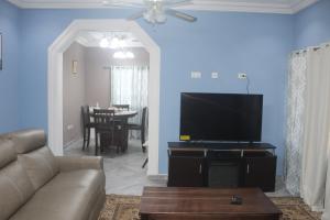 a living room with a couch and a flat screen tv at Coast to Coast Vacation Home in Winneba