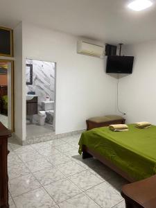 - une chambre avec un lit vert et un miroir dans l'établissement Flavio Reyes, à Manta
