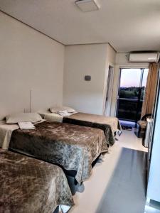 a hotel room with three beds and a window at Hotel Pousada Friedenau in Hulha Negra +24 photos