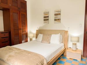 um quarto com uma cama com lençóis brancos e 2 candeeiros em Apartamento en el Corazón de Casco Viejo Panamá 10 na Cidade do Panamá
