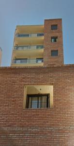 a brick building with a tall building in the background at Cba Rent in Cordoba