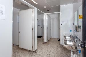 a bathroom with white walls and silver stalls at Tidewater Motel and Budget Accommodation in Coromandel Town