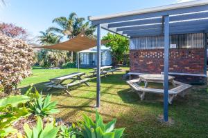 un cortile con tavoli da picnic e un baldacchino di Tidewater Motel and Budget Accommodation a Coromandel