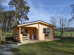 ein kleiner Schuppen mit einer Veranda im Gras in der Unterkunft Pinewood Cabin in Saline