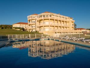 - un grand bâtiment avec une piscine d'eau en face dans l'établissement Résidence Mer & Golf Eugénie, à Biarritz