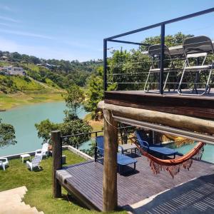 a deck with a hammock and a view of a river at Igarata Cabana da Sol in Igaratá