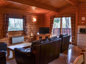 a living room with leather furniture in a log cabin at Ludensian Lodge - Uk37186 in Legbourne