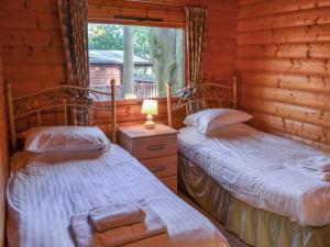 two beds in a log cabin with a window at Ludensian Lodge - Uk37186 in Legbourne