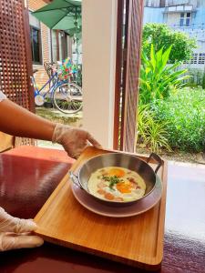 a person holding a pan of soup on a tray at ฮักเคียงโขง HUG Khieng Khong Nongkhai Hostel in Nong Khai
