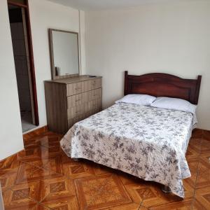 a bedroom with a bed with a dresser and a mirror at Apart Hotel Cabral in Lima