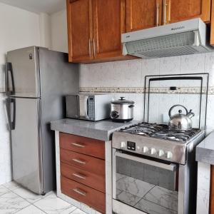 a kitchen with a stove and a refrigerator at Apart Hotel Cabral in Lima