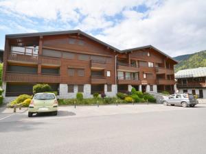 a large building with cars parked in a parking lot at Bel appartement 2 chambres près des pistes, centre station, parking, WIFI, balcon exposé sud - FR-1-684-11 in Morzine +2 photos