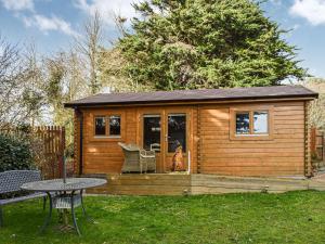 a small wooden cabin with a table and a patio at Cherry Orchard Lodge in West Quantoxhead