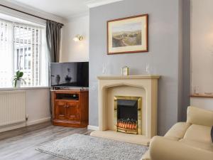 a living room with a fireplace and a tv at Haweswater Cottage in Coundon