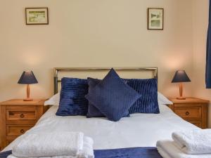 sypialnia z łóżkiem z niebieskimi poduszkami i 2 lampami w obiekcie Haweswater Cottage w mieście Coundon
