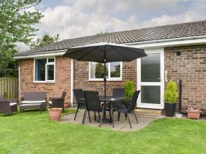 a patio with a table and chairs and an umbrella at Haweswater Cottage in Coundon