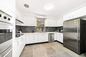 een keuken met witte kasten en een roestvrijstalen koelkast bij 4 Bedroom house 500M to Drummoyne Bay Run in Sydney