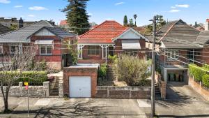 een rood bakstenen huis met een witte garage bij 4 Bedroom house 500M to Drummoyne Bay Run in Sydney