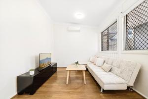a white living room with a couch and a table at 4 Bedroom house 500M to Drummoyne Bay Run in Sydney