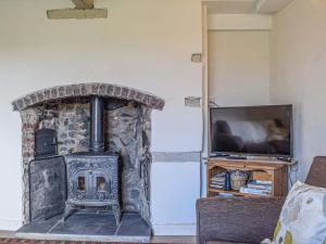a stone fireplace in a living room with a tv at Pentre Cwm Bach in Llansilin
