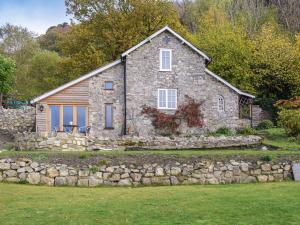 a stone house with a stone wall at Pentre Cwm Bach in Llansilin