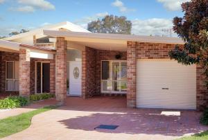 una casa in mattoni con una porta bianca del garage di The Atrium a Shoal Bay