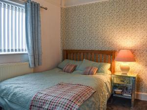 a bedroom with a bed and a lamp and a window at Britannic Chambers Apartment in Blaenau-Ffestiniog