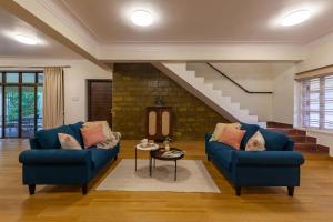 a living room with two blue couches and a staircase at StayVista's V Square - Enjoy a pool and indoor games for a leisurely stay in Lonavala