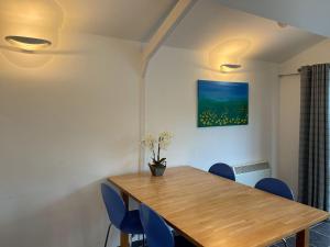 The Lodge At The Lake House في Ifold: غرفة طعام مع طاولة خشبية وكراسي زرقاء