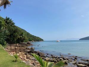 a rocky beach with people swimming in the water at Casa do Carlos, praia da Enseada Ubatuba-SP in Ubatuba