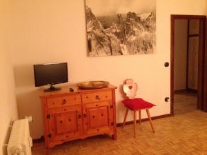 una camera con TV, sedia e cassettiera in legno di Casa ai Dossi a Bellamonte