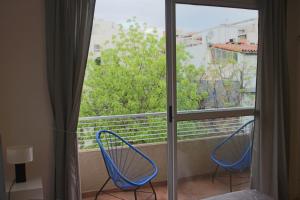 2 blaue Stühle auf einem Balkon mit Fenster in der Unterkunft AA Naon apart in Buenos Aires