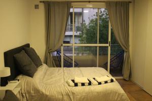 1 dormitorio con cama con almohadas y ventana en AA Naon apart en Buenos Aires