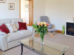 uma sala de estar com um sofá e um vaso de flores em Stronvaar em Stranraer
