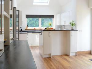 a kitchen with white cabinets and a large window at Stronvaar in Stranraer