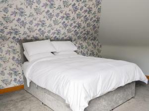 uma cama num quarto com papel de parede floral em Stronvaar em Stranraer