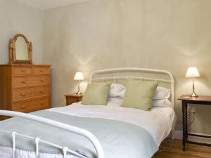 um quarto com uma cama branca com 2 candeeiros e uma cómoda em Campbell Cottage em Windermere