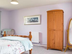 a bedroom with a bed and a wooden cabinet at Furzy Cottage in Haverfordwest