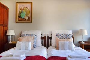 a bedroom with two beds and a picture on the wall at Chesham House in Hermanus